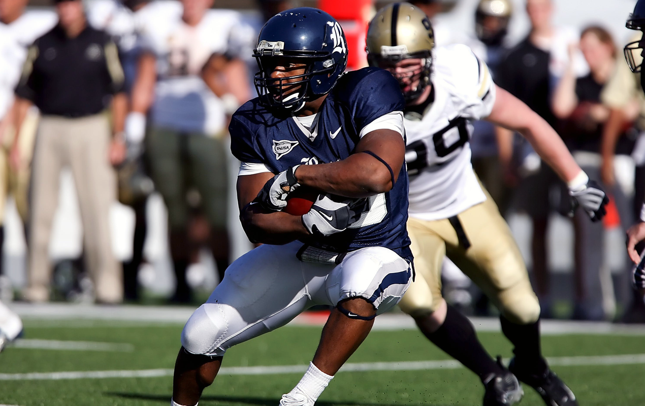 Wide Receiver breaking through a tackle during a college football game.